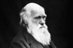 Charles Darwin mustavalkokuvassa mustalla taustalla. Puolilähikuva